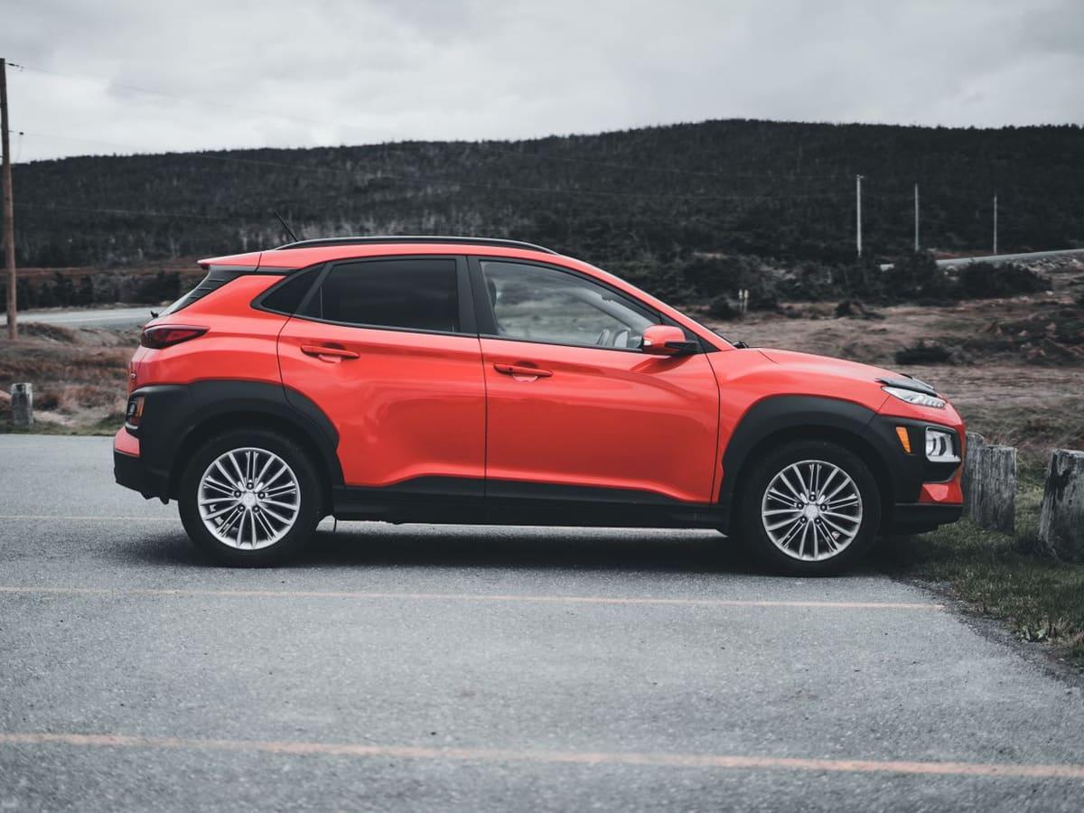 Red compact SUV parked by a hillside road