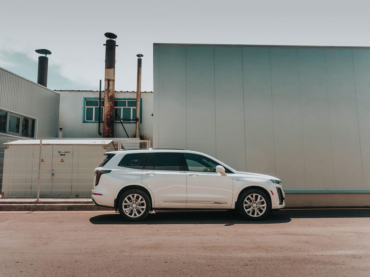White seven-seat SUV parked beside an industrial building