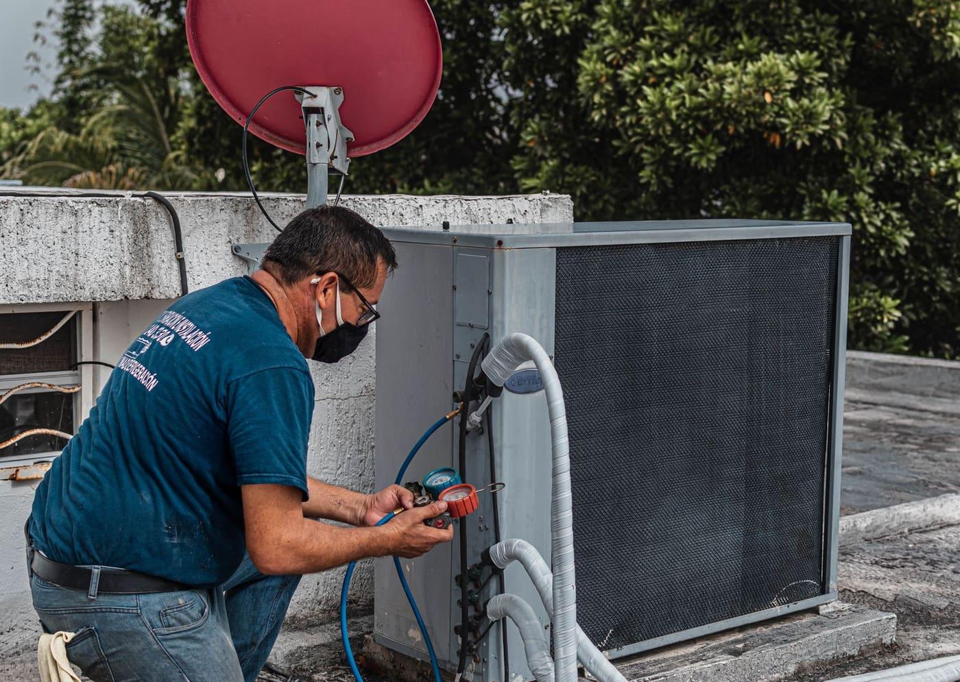 Technician checking an air conditioner unit with a gauge